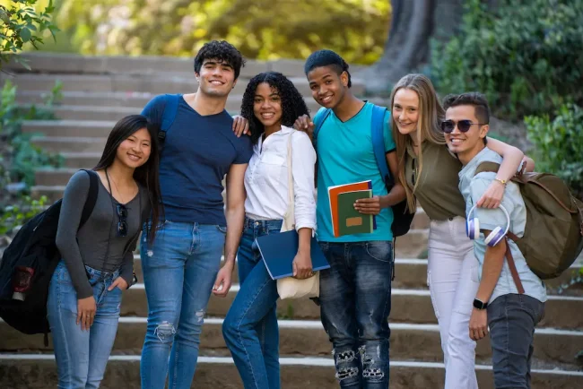 Group of young multiracial students waving at the camera on some stairs