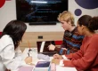 Diverse group of college students studying IT together at table in school library and using laptop with code lines on screen